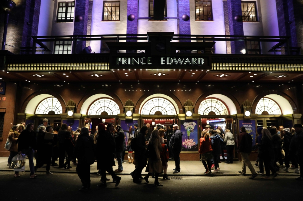 Theatre-goers wearing masks arrive for an evening show of 