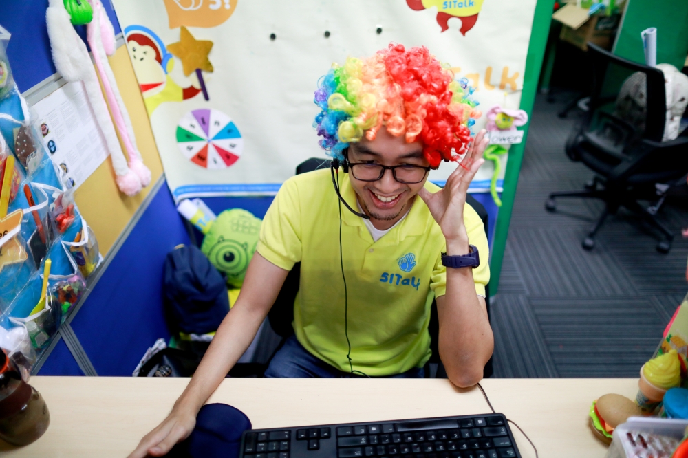 A Filipino online tutor wears a wig as he talks to students from a computer in the head office of 51Talk, as the spread of the coronavirus disease (COVID-19) continues, in Pasig City, Metro Manila, Philippines March 12, 2020. Picture taken March 12, 2020.