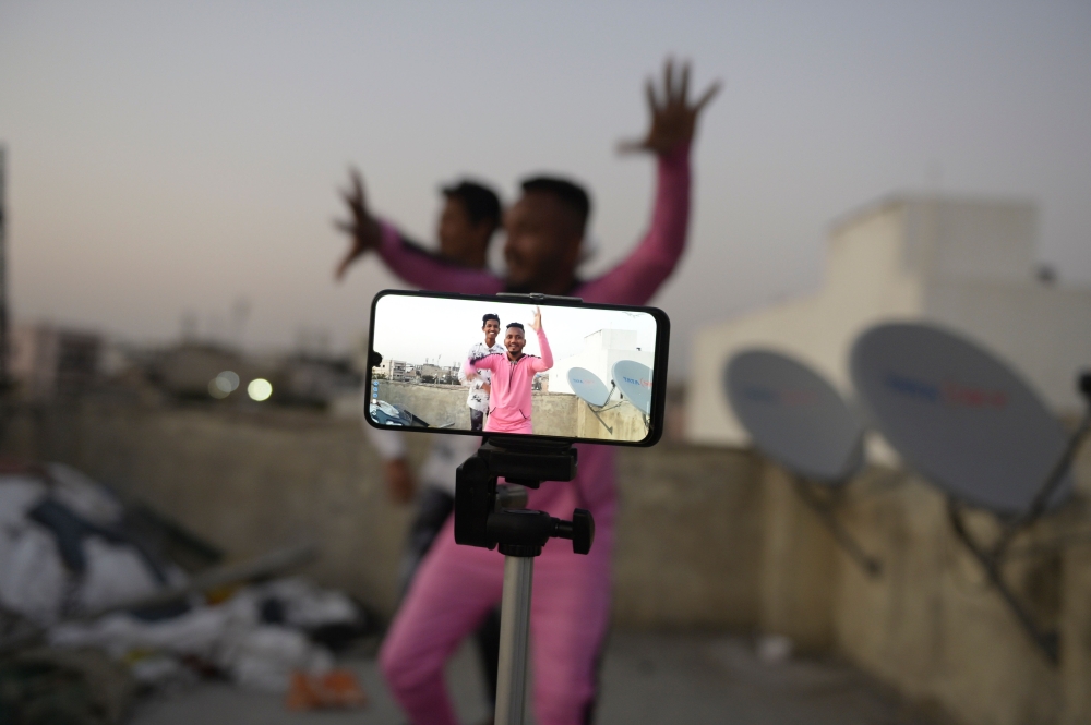 In this file photo taken on February 14, 2020 youths act in front of a mobile phone camera while making a TikTok video on the terrace of their residence in Hyderabad. This is TikTok's time./ AFP / NOAH SEELAM