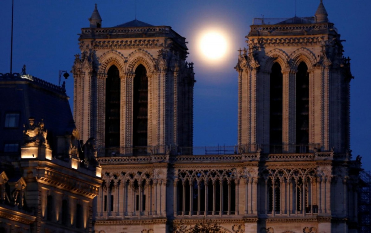 The pink supermoon rises between the two towers of Notre Dame Cathedral, which was damaged in a devastating fire almost one year ago, ahead of Easter celebrations to be held under lockdown imposed to slow the spread of the coronavirus disease (COVID-19), 