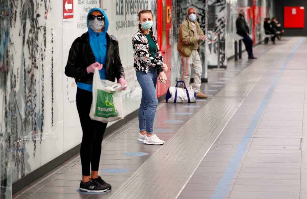 People stand on social distancing signs as they wait for a train at the San Giovanni subway station as the spread of the coronavirus disease (COVID-19) continues, in Rome, Italy, April 28, 2020. Reuters/Guglielmo Mangiapane
