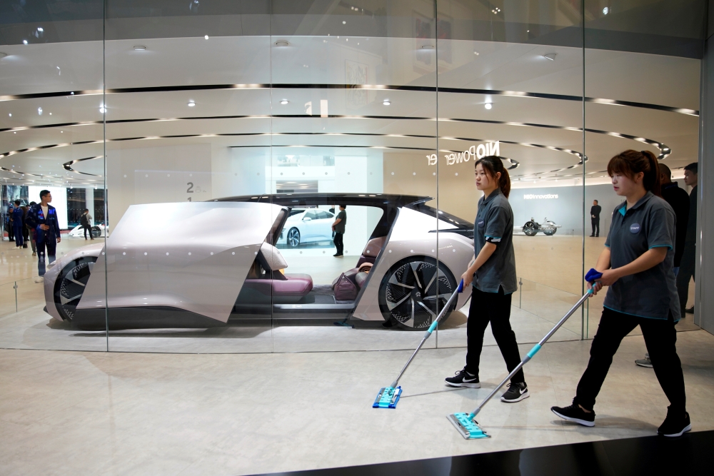 FILE PHOTO: Cleaners are seen next to a self-driving electric concept car NIO Eve displayed at the second media day for the Shanghai auto show in Shanghai, China April 17, 2019. REUTERS/Aly Song
