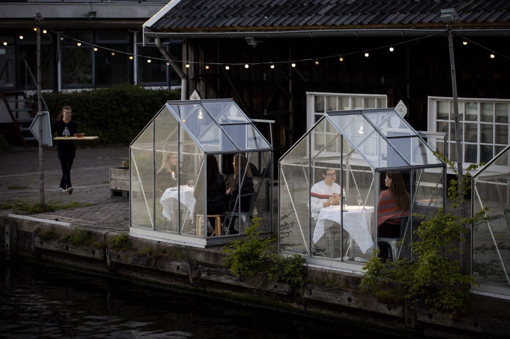 People have dinner in a so-called quarantine greenhouses in Amsterdam, on May 5, 2020 as the country fights against the spread of the COVID-19, the novel coronavirus. Netherlands OUT / AFP / ANP / Robin VAN LONKHUIJSEN
