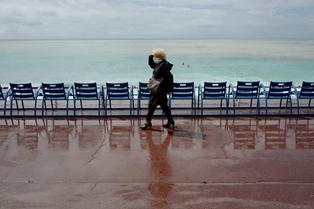 A woman wears a face mak as she walks down the Promenade des anglais avenue in Nice, French Riviera, on May 11, 2020, on the first day of the lift of lockdown measures set up on March 17 in France to curb the spread of the COVID-19 caused by the novel cor