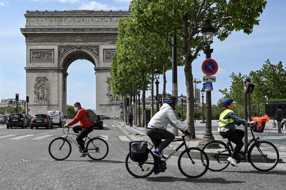 In this file photo taken on May 11, 2020 People ride on their bicycles in The Champs Elysees Avenue , in Paris, on May 11, 2020, on the first day of France's easing of lockdown measures in place for 55 days to curb the spread of the COVID-19 pandemic, cau