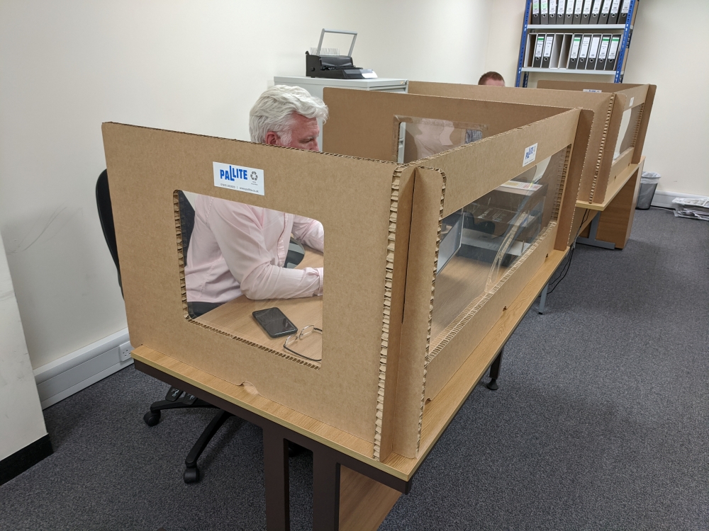 Staff at Pallite work at their desks while protected from colleagues by the company’s cardboard social distancing screens, following the outbreak of the coronavirus disease (COVID-19), at their HQ in Wellingborough, Britain May 27, 2020. REUTERS/Stuart Mc