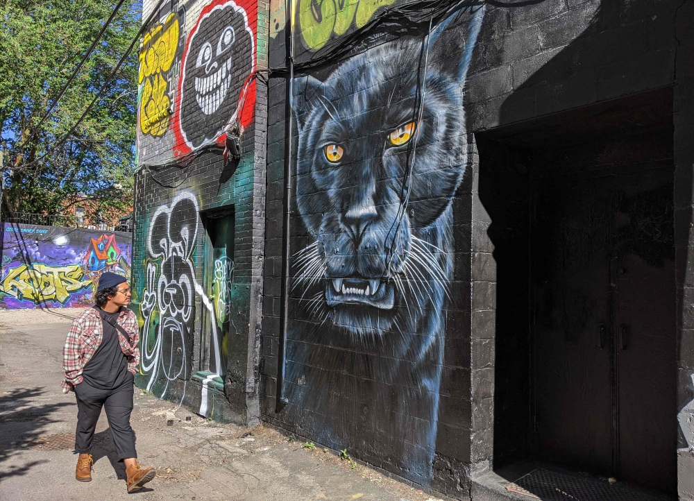 Graffiti artist Moises Frank walks past the Graffiti Alley, in Toronto, on June 12, 2020. AFP / Olivier Monnier 