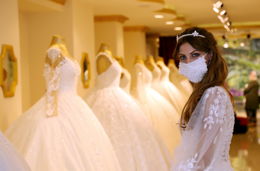 An employee presents a wedding dress with a mask at the Mezopotamya bridal gowns shop, amid the spread of the coronavirus disease (COVID-19), in Diyarbakir, Turkey, June 29, 2020. Picture taken June 29, 2020. REUTERS/Sertac Kayar