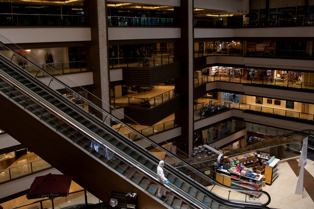 A janitor wearing a hazmat suit to prevent the spread of coronavirus disease (COVID-19), rides an escalator in an almost empty shopping mall in Mandaluyong City, Metro Manila, Philippines, June 3, 2020. REUTERS/Eloisa Lopez/File Photo