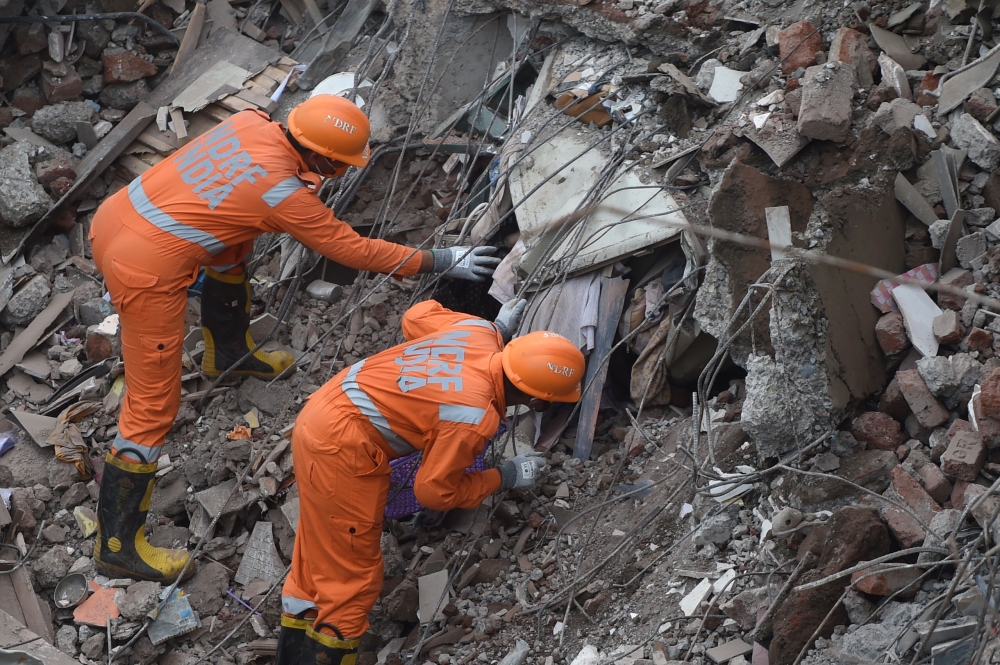 Rescue workers search for survivors in the rubble of a collapsed five-storey apartment building in Mahad on August 25, 2020. / AFP / Punit PARANJPE