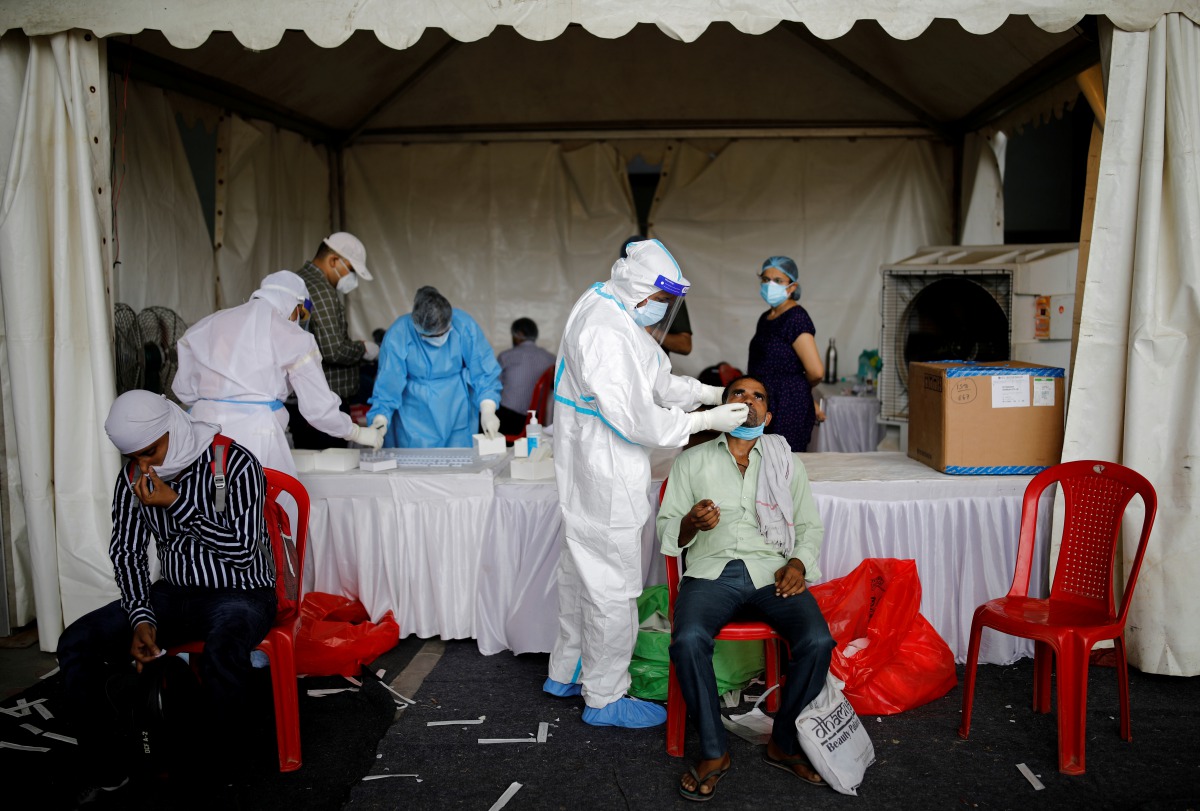 FILE PHOTO: A healthcare worker wearing personal protective equipment (PPE) takes a swab from a migrant worker, who returned to Delhi from his native state, for a rapid antigen test at a bus terminal, amidst the coronavirus disease (COVID-19) outbreak in 