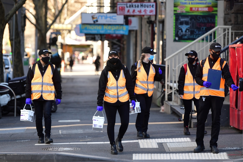 Cleaners walk down a street as the city operates under lockdown in response to an outbreak of the coronavirus disease (COVID-19) in Melbourne, Australia, September 3, 2020. AAP Image/Erik Anderson via REUTERS