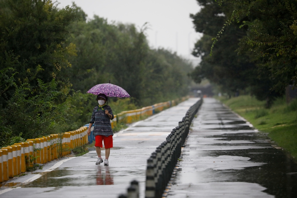 A woman takes a walk as it rains amid the coronavirus disease (COVID-19) pandemic at a Han River park in Seoul, South Korea, September 2, 2020. REUTERS/Kim Hong-Ji/File Photo