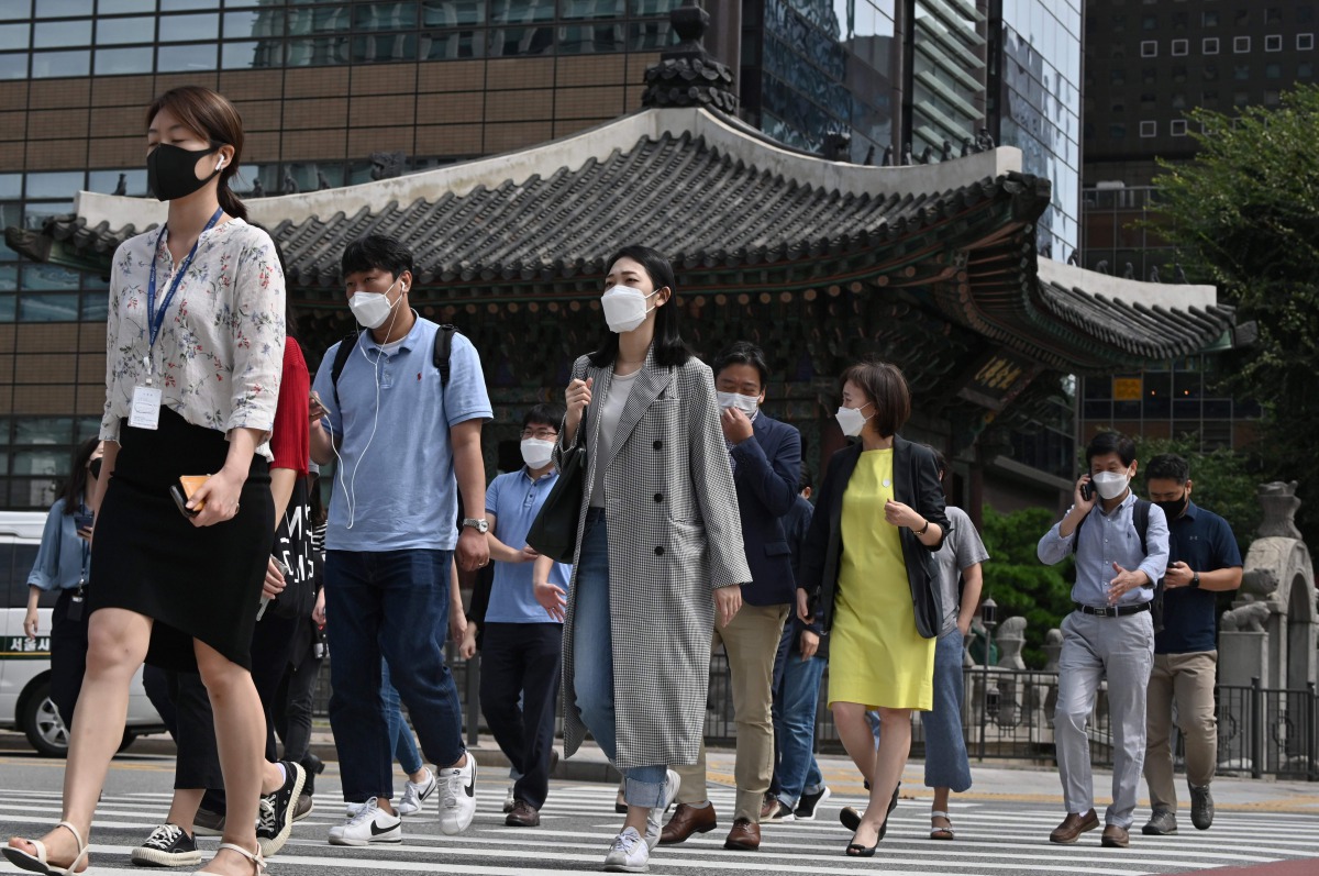 People wearing face masks cross a road in Seoul on September 11, 2020. South Korea largely overcame an early COVID-19 coronavirus outbreak with extensive tracing and testing, but is now battling several outbreaks. / AFP / Jung Yeon-je
