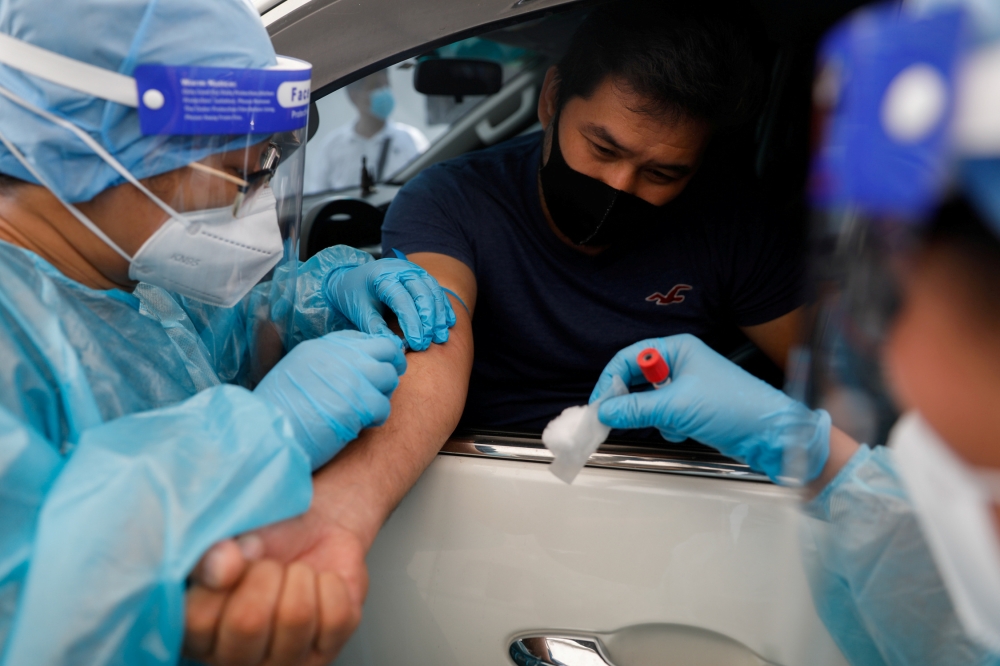 A healthcare worker takes blood sample from a passenger at a coronavirus disease (COVID-19) drive-thru testing center in Manila, Philippines, July 15, 2020. REUTERS/Eloisa Lopez/File Photo