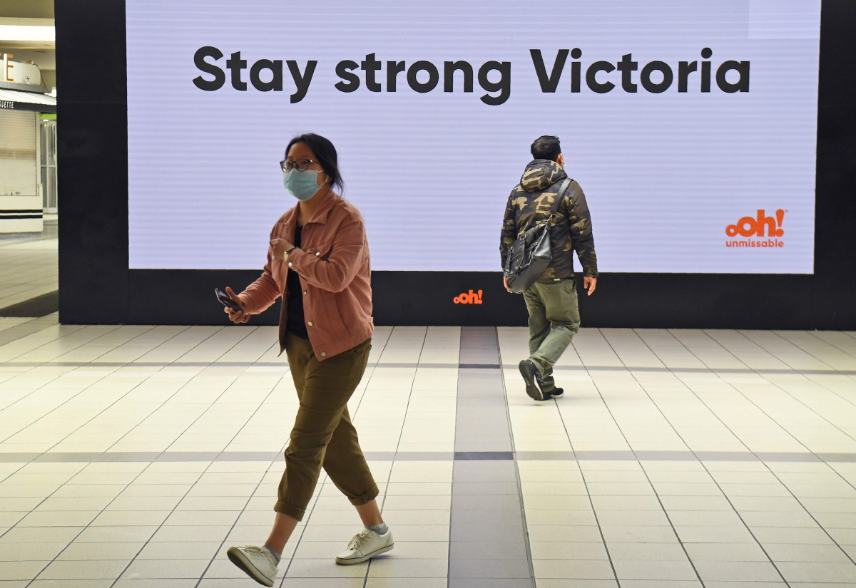 People pass a sign at Melbourne's Flinders Street station on September 17, 2020. Australia's unemployment rate on September 17 fell slightly to 6.8 percent in August, spurring hopes that the worst of a coronavirus-fuelled recession may have passed. / AFP 