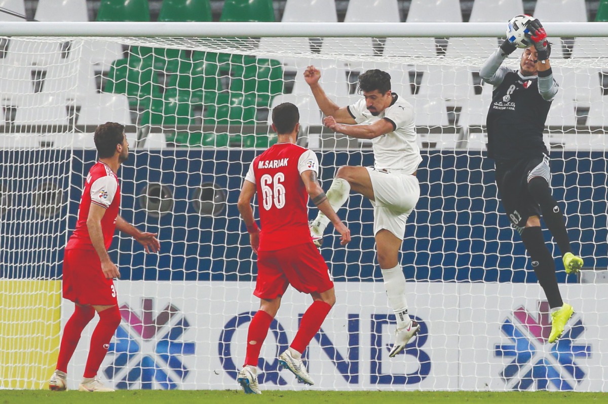 Persepolis’ goalkeeper Hamed Lak (right) grabs the ball ahead of Sadd’s forward Baghdad Bounedjah during the AFC Champions League Round of 16 match, played at the Education Stadium yesterday