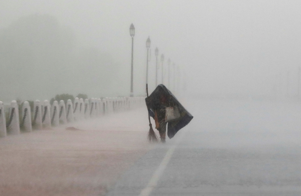A woman covers herself with a plastic sheet as she walks during heavy rains in New Delhi, India, July 21, 2020. REUTERS/Adnan Abidi/File Photo