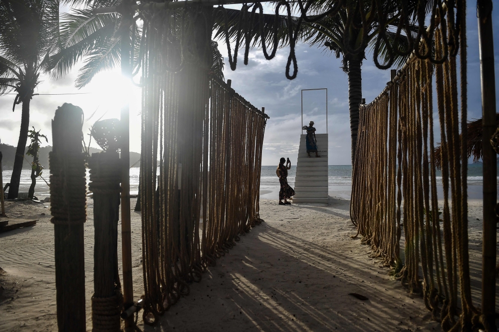 This picture taken on October 1, 2020 shows visitors taking pictures on a set of stairs on Patong beach in Phuket, which has seen a lack of tourists due to ongoing restrictions relating to the COVID-19 novel coronavirus. / AFP / Lillian SUWANRUMPHA