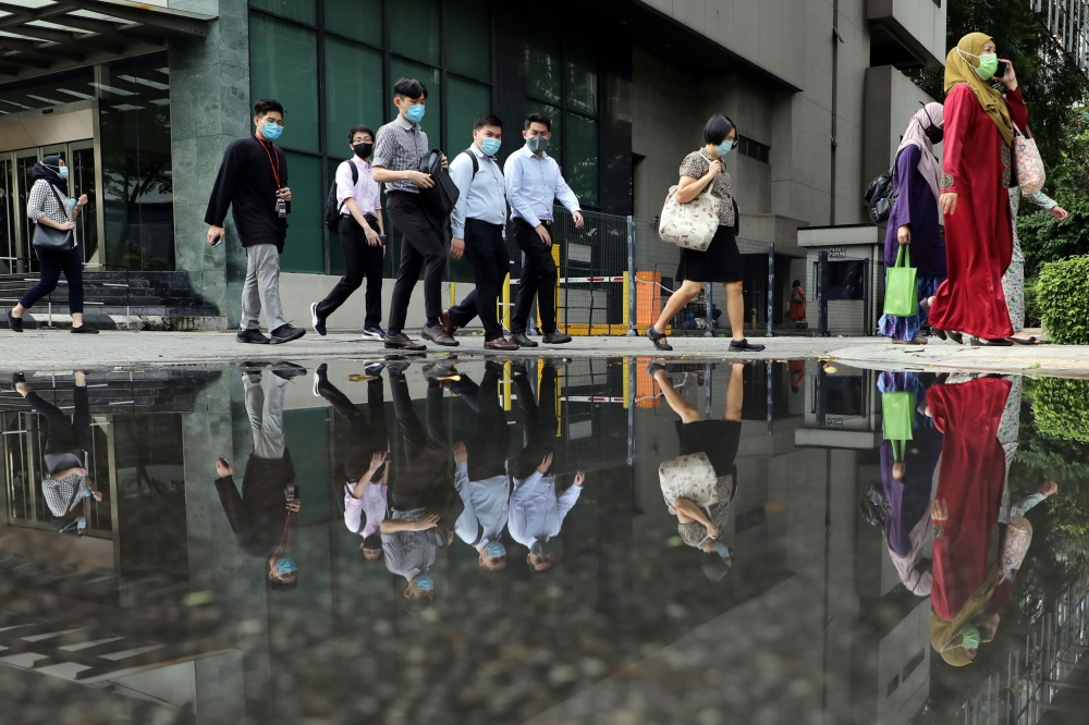 People wearing protective masks are reflected in a water puddle as they cross a street, amid the coronavirus disease (COVID-19) outbreak in Kuala Lumpur, Malaysia October 2, 2020. REUTERS/Lim Huey Teng