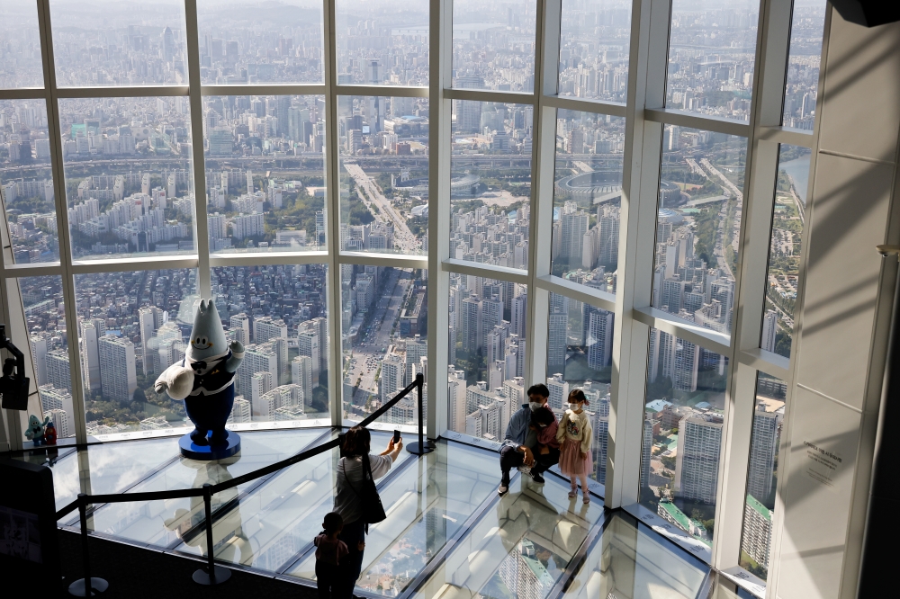 A family wearing masks to avoid the spread of the coronavirus disease (COVID-19) takes souvenir photos at the Seoul Sky Observatory in Seoul, South Korea, October 5, 2020. REUTERS/Kim Hong-Ji