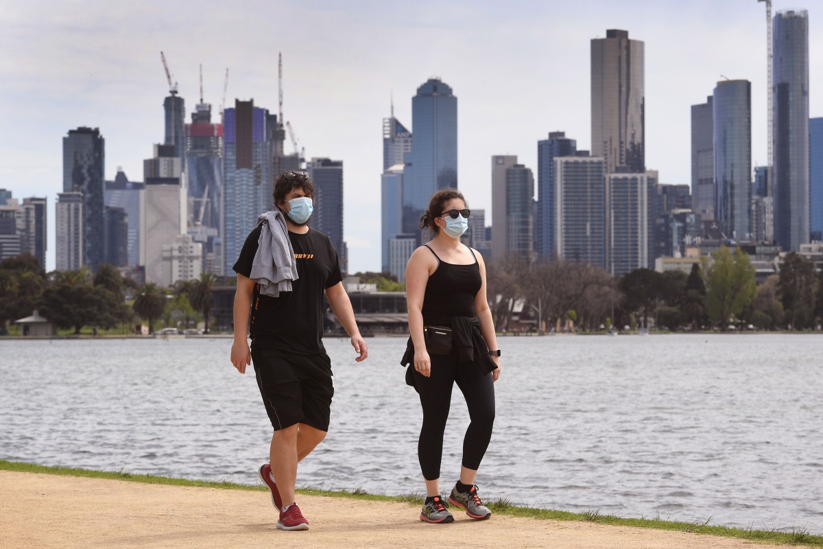 People walk around Melbourne's Albert Park Lake on October 12, 2020, as they use their two hours daily exercise allowed during the stage four restrictions due to the COVID-19 coronavirus outbreak. / AFP / William WEST

