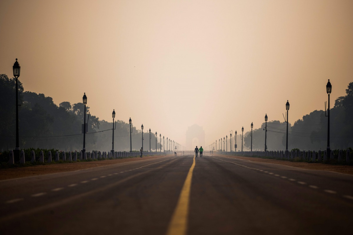 People walk along Rajpath street during a smoggy morning in New Delhi on October 15, 2020. / AFP / Jewel SAMAD
