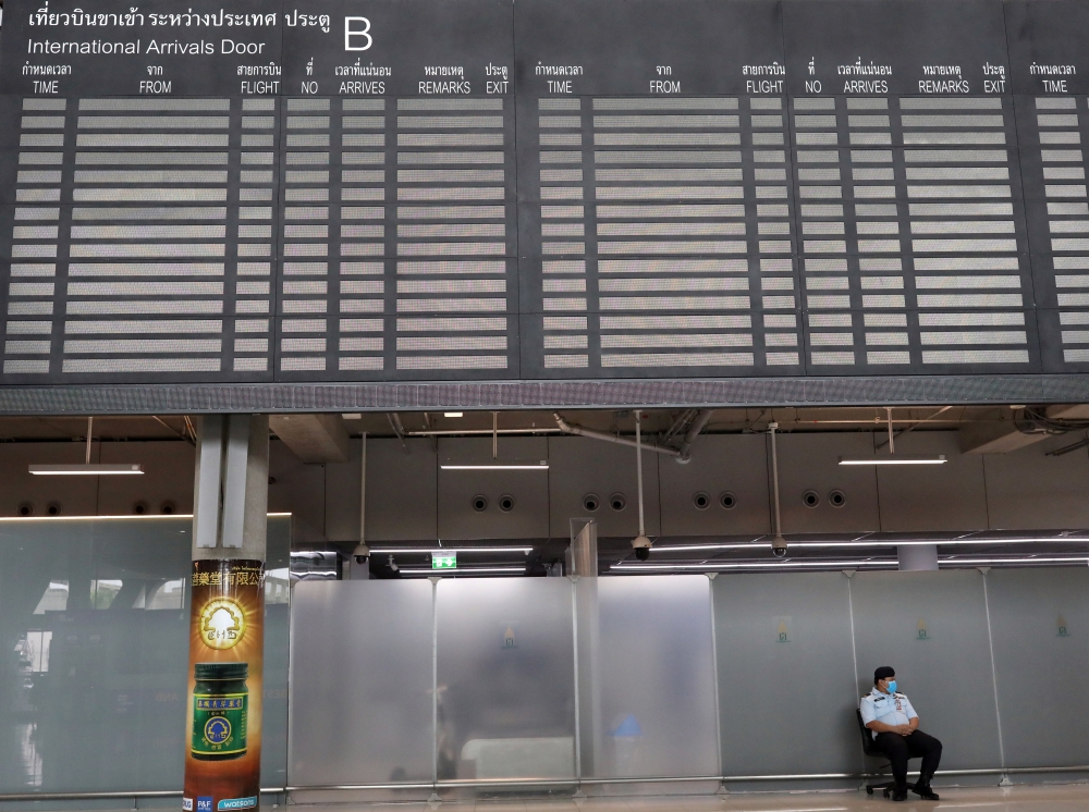 A staff member sits under the arrivals flight information board at Suvarnabhumi Airport during the coronavirus disease (COVID-19) pandemic in Bangkok, Thailand, October 12, 2020. REUTERS/Soe Zeya Tun