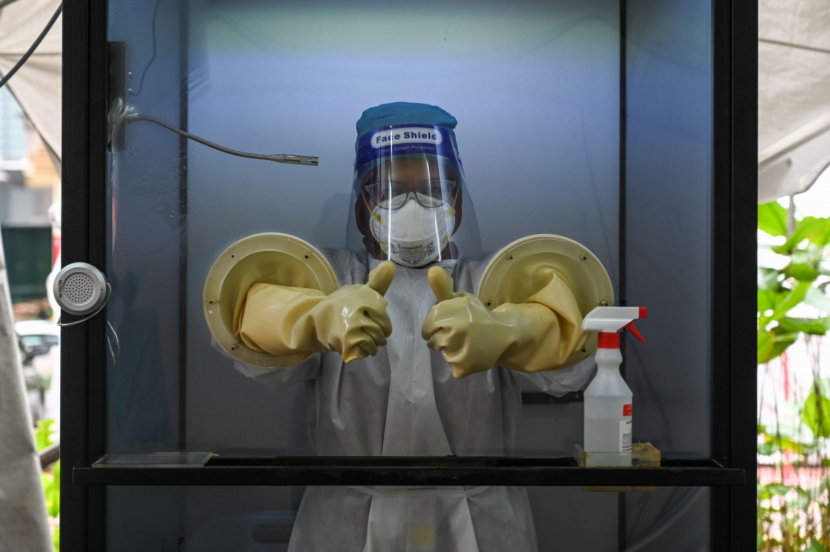 TOPSHOT - A health worker gives a thumbs-up as she stands in a non-contact chamber called the 