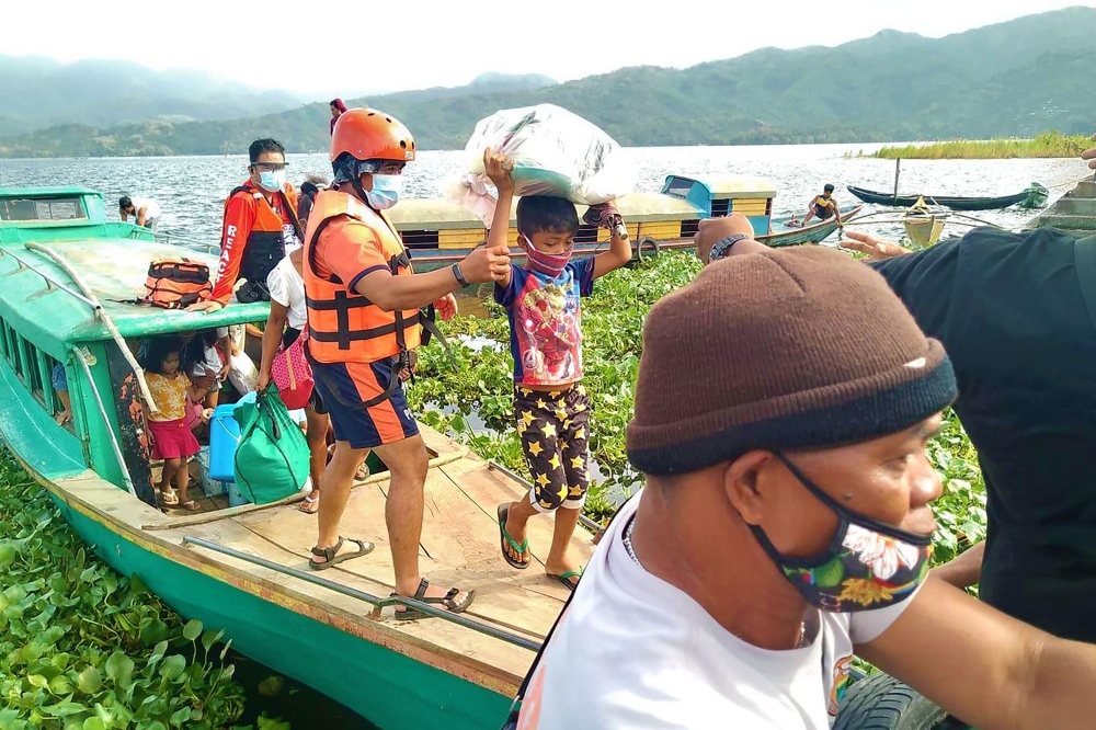 A handout photo taken on October 31, 2020 from the Facebook page of Philippine Coast Guard, shows personnels from the coast guard evacuating residents from the coastal villages of Buhi town, Camarines Sur province, south of Manila, to a safer place, ahead