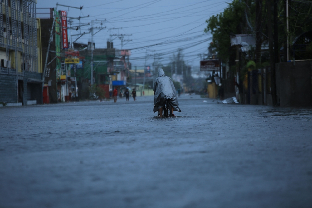 A resident cycles along a flooded street due to heavy rains brought by Super Typhoon Goni in Legazpi City, Philippines' Abay province on November 1, 2020. / AFP / Charism SAYAT