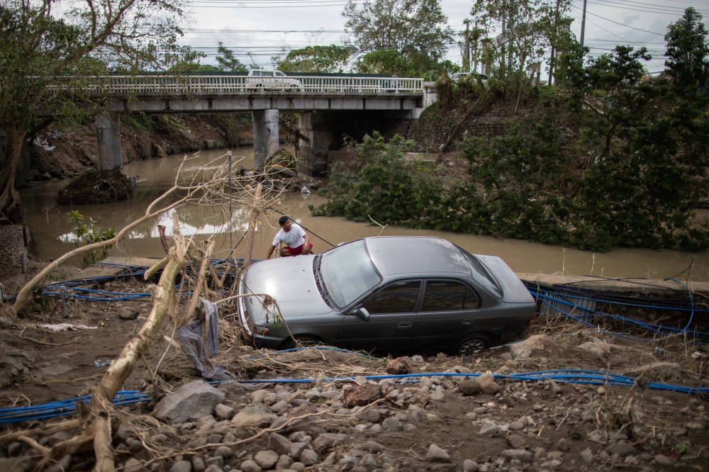 A man sits beside a car, washed away by floods caused by Typhoon Goni, in Barangay San Isidro, Batangas City, Philippines, November 2, 2020. REUTERS/Eloisa Lopez