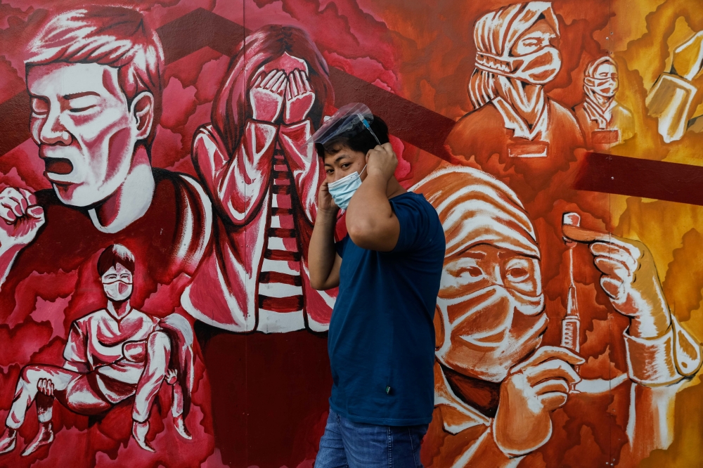 A man fixes his mask for protection against the coronavirus disease (COVID-19) as he walks past a mural dedicated to healthcare workers, in Pasig City, Metro Manila, Philippines, October 30, 2020. REUTERS/Eloisa Lopez