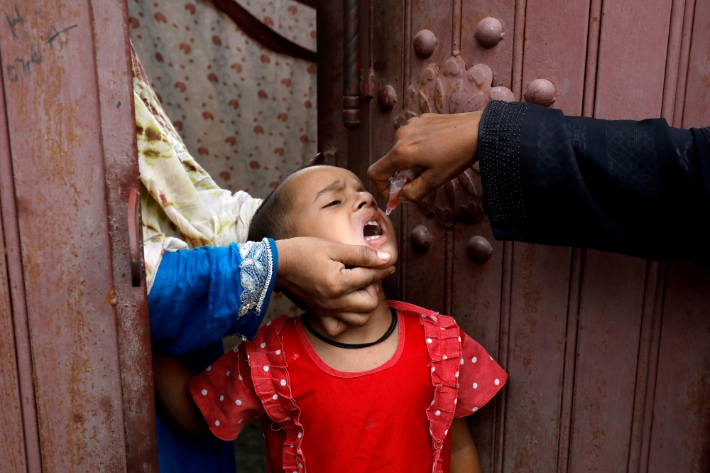 A girl receives polio vaccine drops, during an anti-polio campaign, in a low-income neighborhood as the spread of the coronavirus disease (COVID-19) continues, in Karachi, Pakistan July 20, 2020. REUTERS/Akhtar Soomro/File Photo