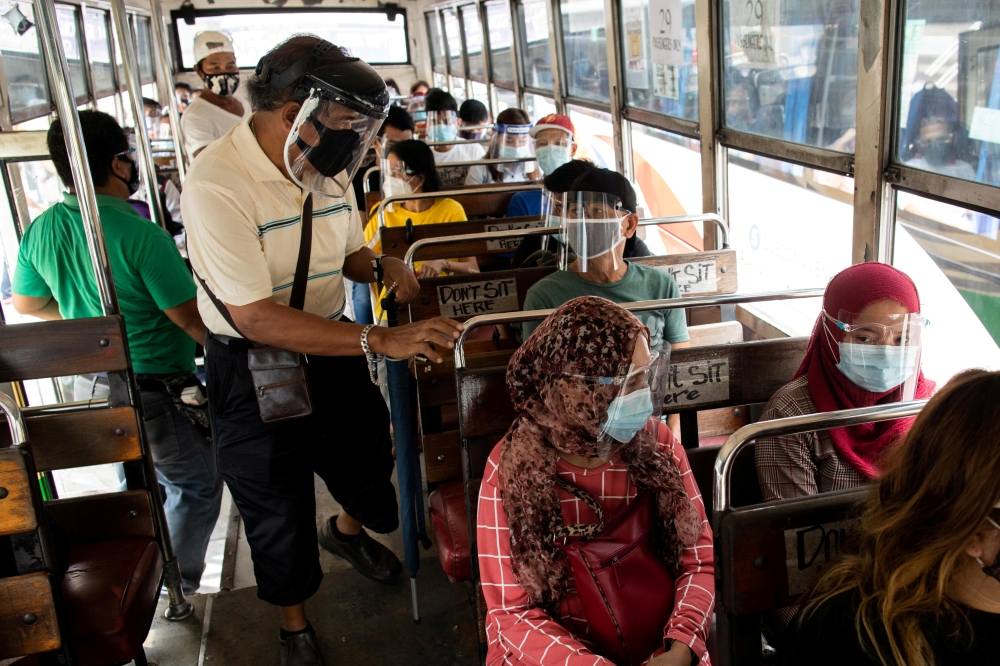 Passengers on board a bus wear face masks and face shields, both mandatory in public transportation, to help curb coronavirus disease (COVID-19) infections, in Quezon City, Metro Manila, Philippines, August 19, 2020. REUTERS/Eloisa Lopez/File Photo