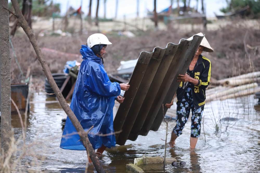 Residents carry part of a damaged roof following high winds and rain brought by Typhoon Vamco as it made landfall in Thua Thien Hue province on November 15, 2020. / AFP / Huy THANH
