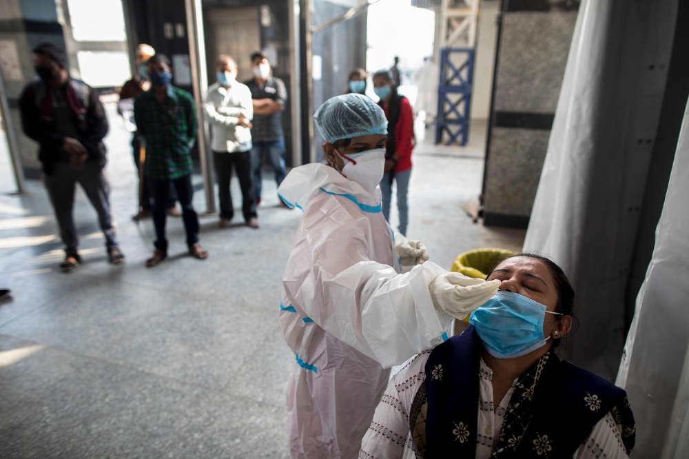 A medical worker collects a swab sample for a Rapid Antigen Test (RAT) for the Covid-19 coronavirus from a passenger before boarding a train at Hazrat Nizamuddin Railway Station in New Delhi on November 10, 2020. / AFP / XAVIER GALIANA