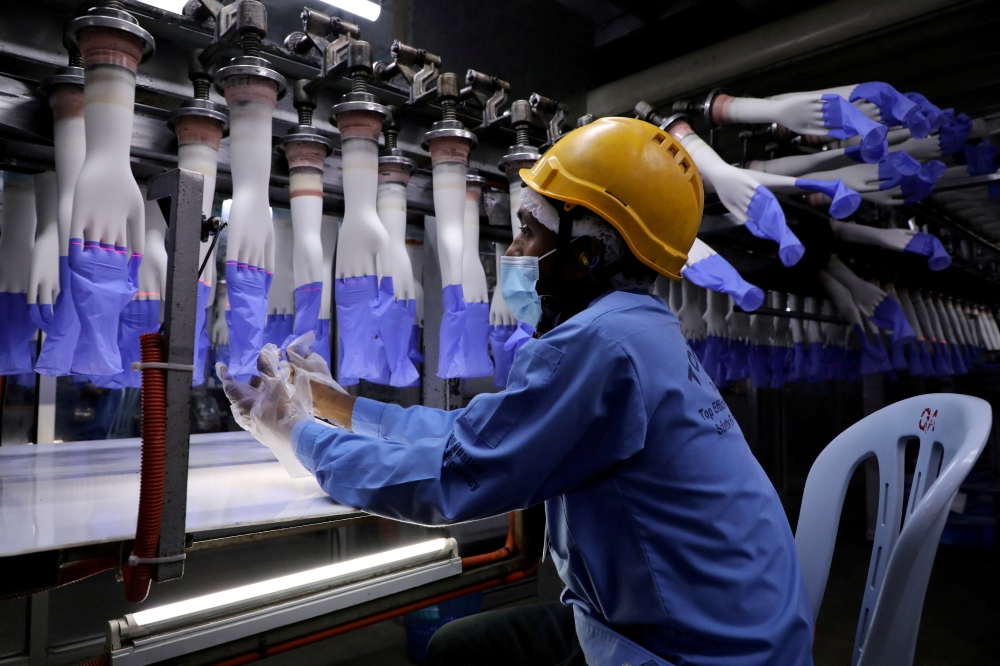 A worker inspects newly-made gloves at Top Glove factory in Shah Alam, Malaysia August 26, 2020. REUTERS/Lim Huey Teng/File Photo