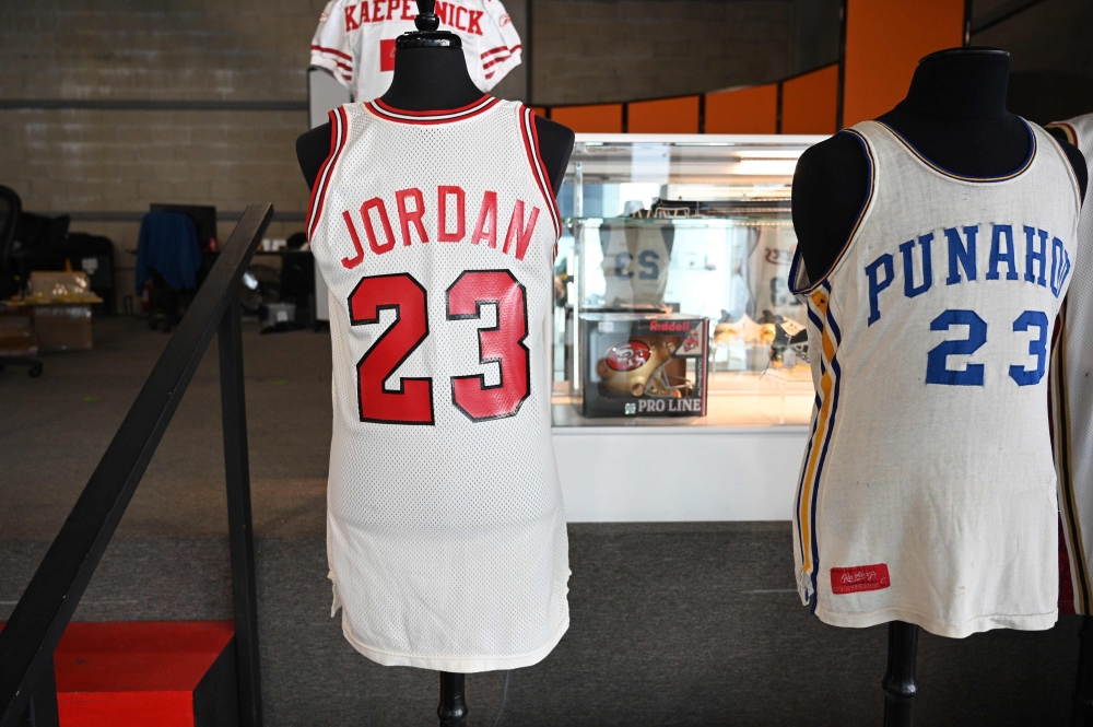 In this file photo taken on November 23, 2020, a Michael Jordan 1984 signing day Chicago Bulls official NBA game jersey is displayed beside US President Barack Obama's 1978-1979 game worn high school basketball jersey from Hawaii's Punahou School at a med