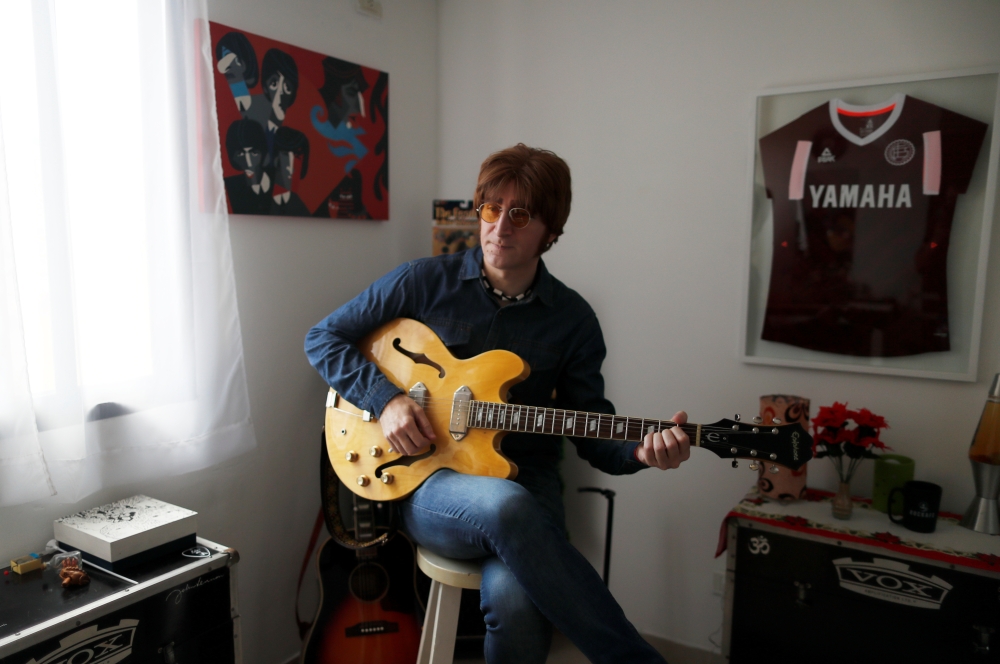 Javier Parisi, who impersonates late former Beatle John Lennon, plays the guitar during an interview with Reuters, in Lanus, on the outskirts of Buenos Aires, Argentina November 18, 2020. Picture taken November 18, 2020. REUTERS/Agustin Marcarian