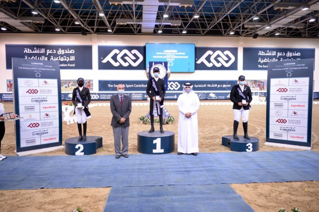 The podium winners of the Medium Level Dressage competition of the sixth round of the Longines Hathab Qatar Equestrian Tour, Jassim Al Jaham Al Kuwari, Maryam Ahmed Alsemaitt and Saoud Ahmed Al Boinin posing for a photograph with officials at the Qatar Eq