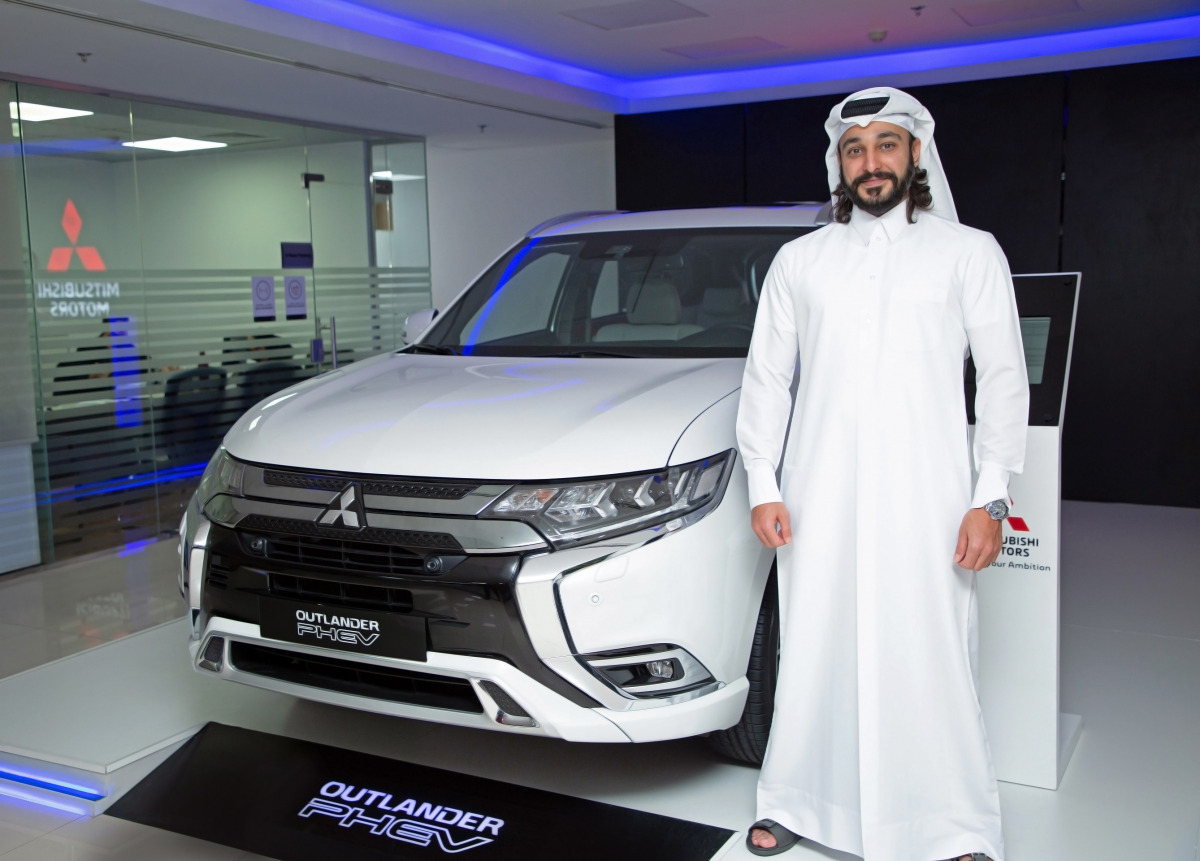 An official posing with the all-new Mitsubishi Outlander PHEV (Plug-In Hybrid Electric Vehicle) at Qatar Automobiles Company's (QAC) showroom in Qatar.