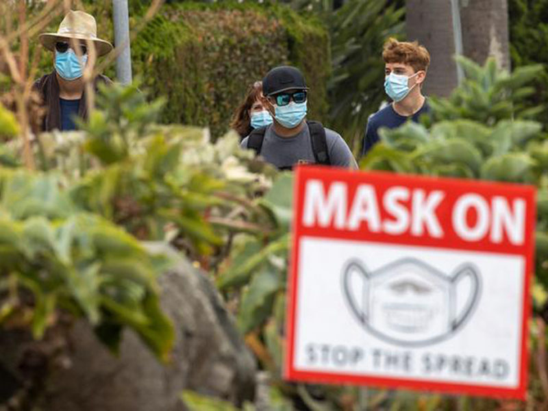 FILE PHOTO: People wear masks as they walk along the side walk in Del Mar, Calif., on July 30, 2020. Mike Blake/Reuters/File Photo
