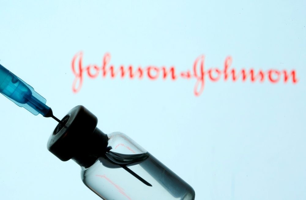 A vial and sryinge are seen in front of a displayed Johnson&Johnson logo in this illustration taken January 11, 2021. REUTERS/Dado Ruvic/Illustration/File Photo