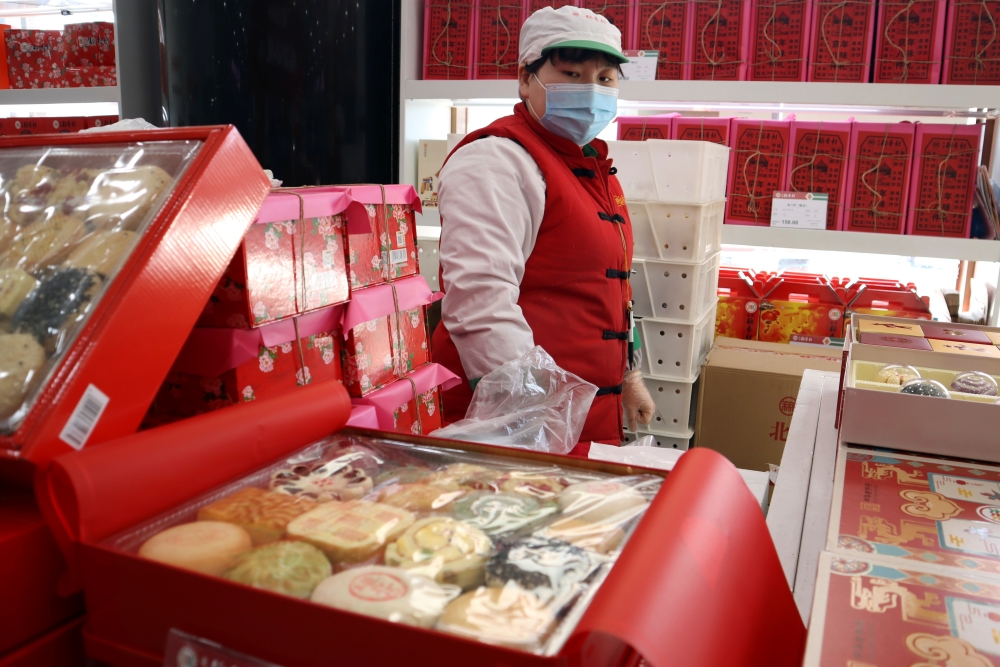 A staff member stands behind Lunar New Year gift sets containing pastries at a food store, following the coronavirus disease (COVID-19) outbreak in Beijing, China February 4, 2021. Reuters/Florence Lo