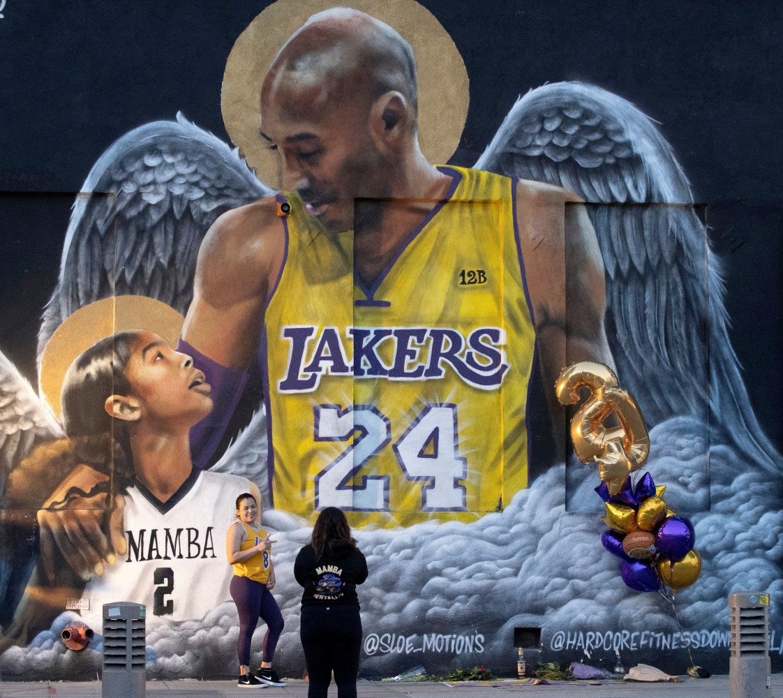 FILE PHOTO: A fan poses by a mural of late Kobe Bryant, who perished one year ago alongside his daughter and seven others when their helicopter crashed into a hillside, in Los Angeles, California, U.S., January 26, 2021. REUTERS/Mario Anzuoni/File Photo
