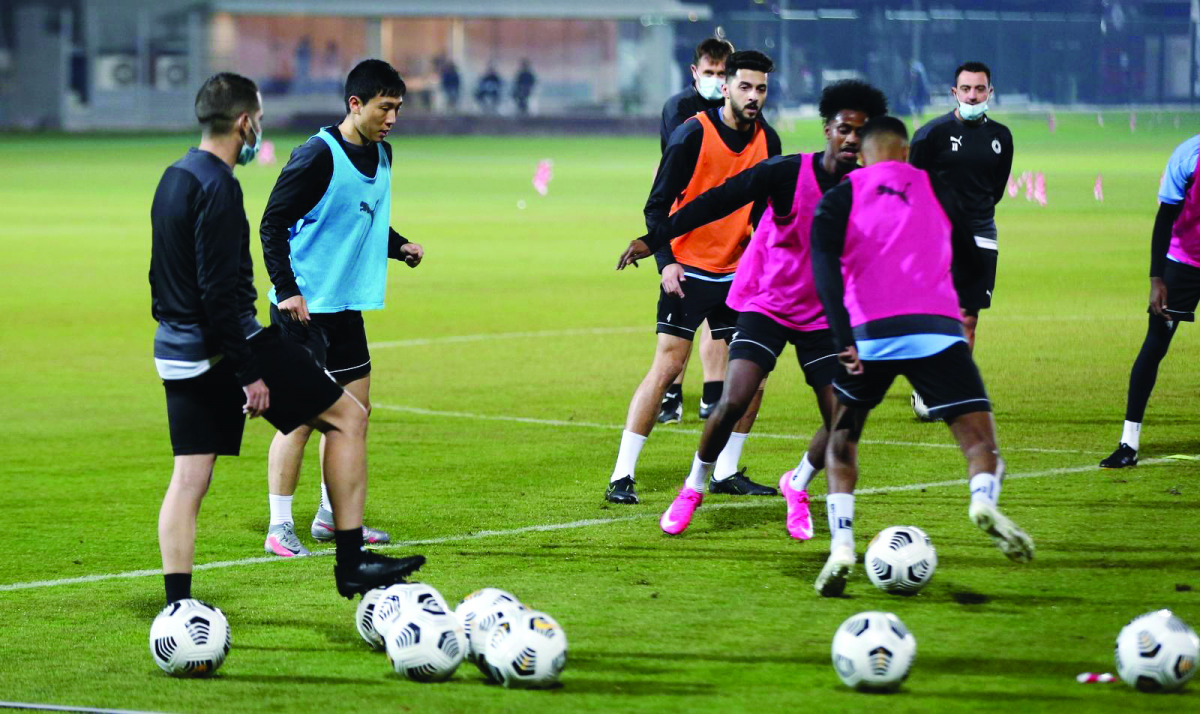 Al Sadd players in action during a practice session as coach Xavi Hernandez looks on.