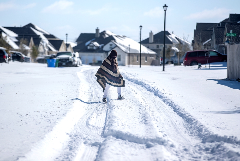 A man walks to his friend's home in a neighborhood without electricity as snow covers the BlackHawk neighborhood in Pflugerville, Texas, U.S. February 15, 2021. Bronte Wittpenn
