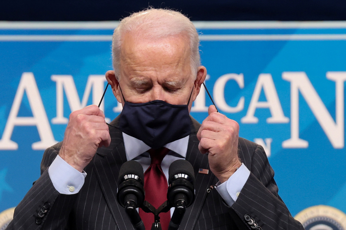 U.S. President Joe Biden removes his face mask as he arrives to announce changes to the main U.S. coronavirus disease (COVID-19) aid program for small businesses during brief remarks in the South Court Auditorium at the White House in Washington, U.S., Fe