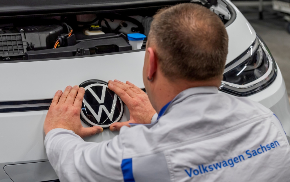 An employee fixes a VW sign at a production line of the electric Volkswagen model ID.3 in Zwickau, Germany, February 25, 2020. REUTERS/Matthias Rietschel/File Photo